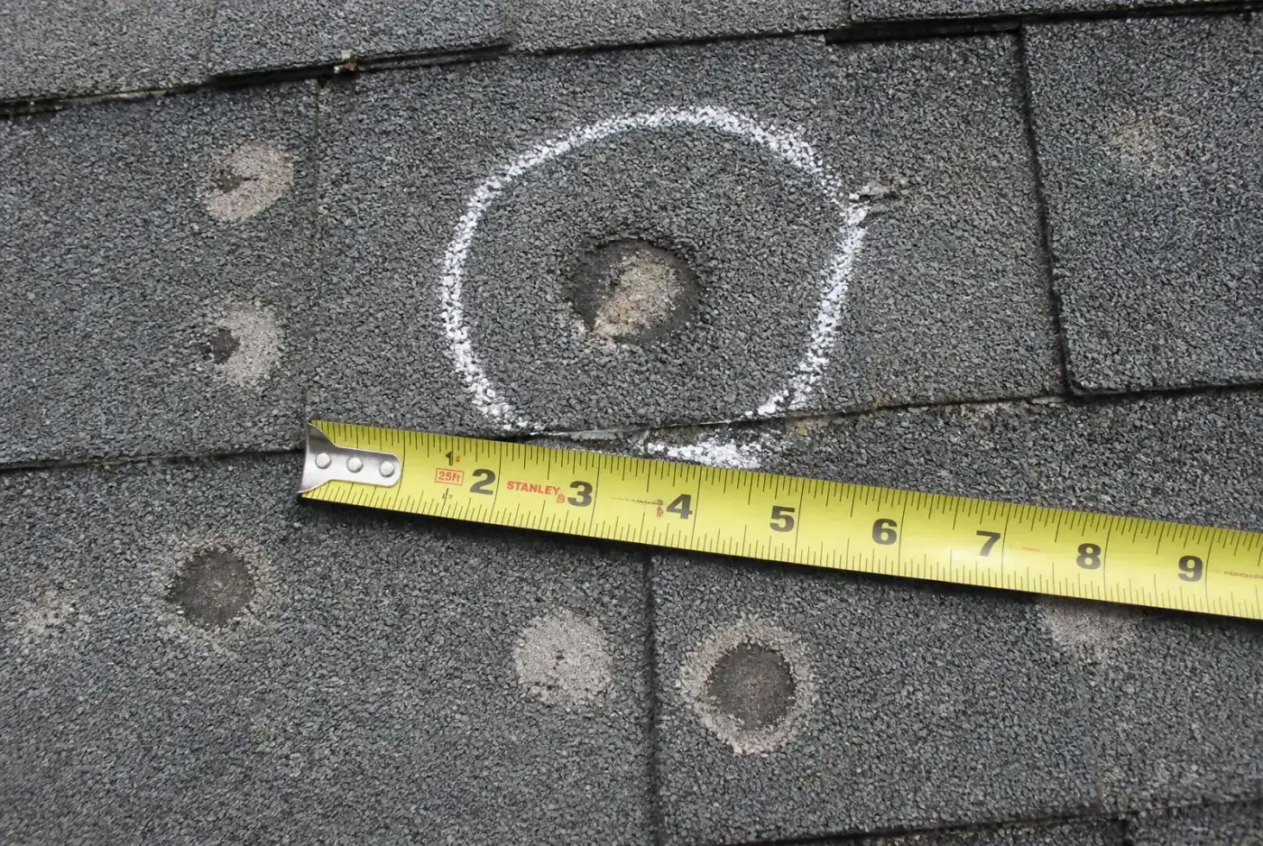 Aftermath of a storm on a residential roof, showing damaged shingles